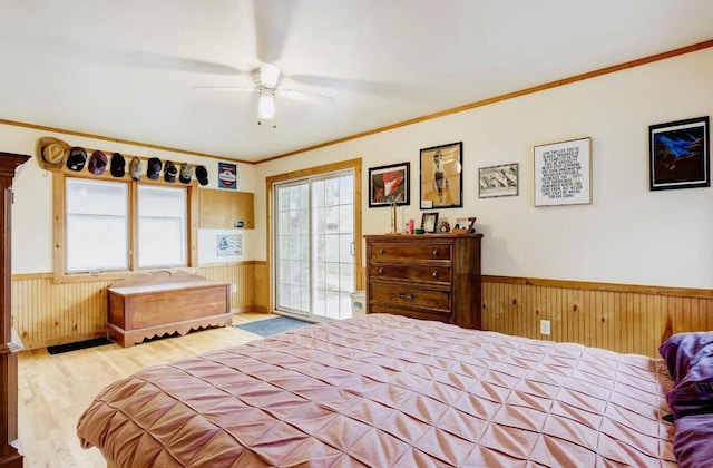 bedroom featuring ornamental molding, wooden walls, light wood-type flooring, and ceiling fan