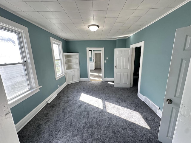 unfurnished bedroom with multiple windows, ornamental molding, and dark colored carpet