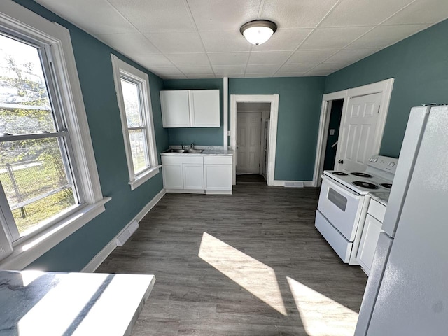 kitchen featuring white cabinetry, dark hardwood / wood-style floors, plenty of natural light, and white appliances