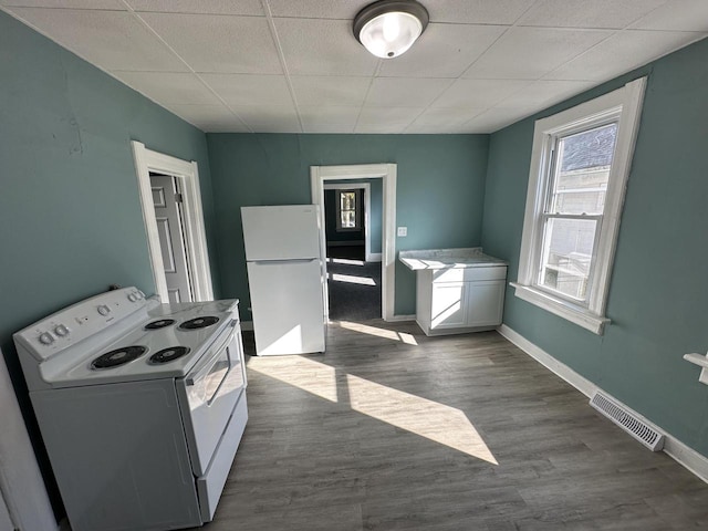 kitchen featuring white appliances, white cabinetry, dark hardwood / wood-style flooring, and a drop ceiling