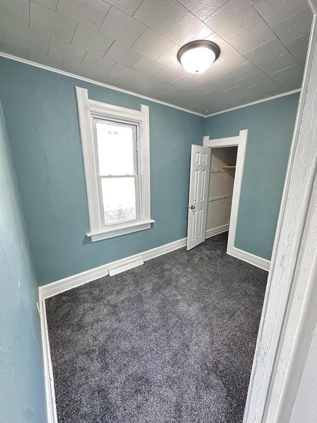 unfurnished bedroom featuring dark carpet and crown molding