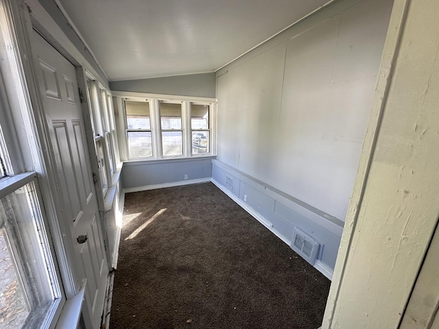 spare room featuring lofted ceiling and dark colored carpet