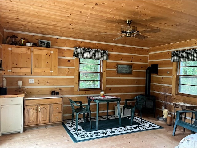 dining space featuring wooden walls, light wood-type flooring, and a healthy amount of sunlight