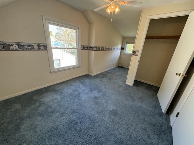 unfurnished bedroom featuring dark colored carpet, multiple windows, vaulted ceiling, and ceiling fan