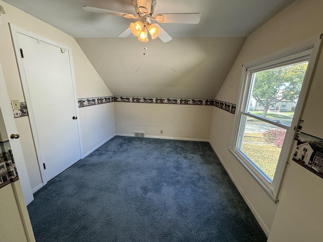 additional living space with dark colored carpet, ceiling fan, and vaulted ceiling