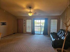 carpeted living room with ceiling fan