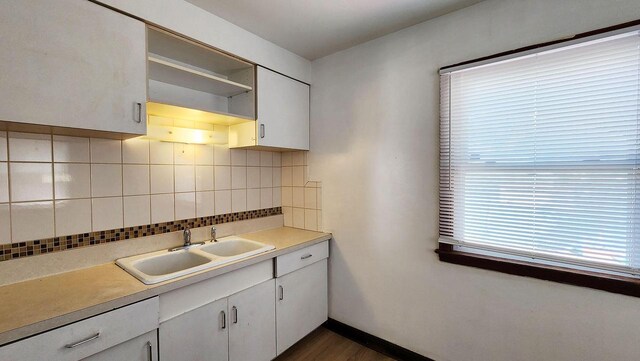 kitchen with decorative backsplash, white cabinetry, sink, and dark hardwood / wood-style floors