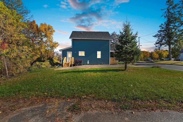 property exterior at dusk featuring a yard