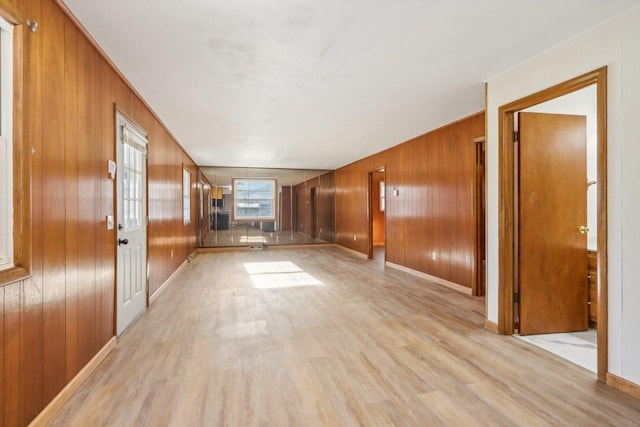 corridor with wood walls and light wood-type flooring