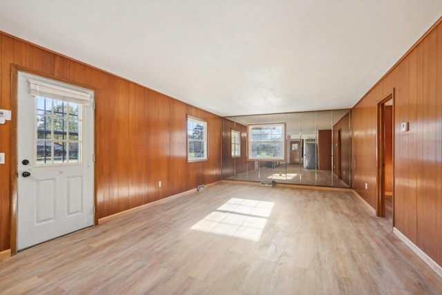 unfurnished living room with light hardwood / wood-style flooring and wooden walls