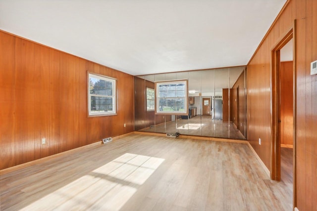 empty room featuring wood walls and light hardwood / wood-style flooring