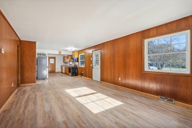 unfurnished living room featuring light hardwood / wood-style floors and wood walls