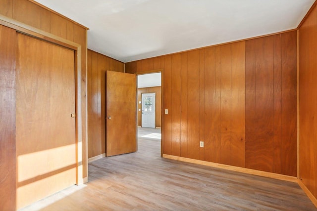 unfurnished room with light hardwood / wood-style flooring and wood walls