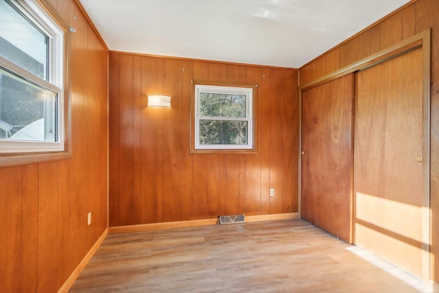 spare room with light hardwood / wood-style floors and wood walls