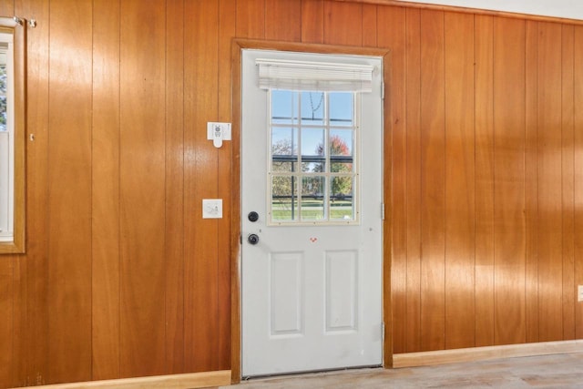 doorway with wooden walls and light wood-type flooring