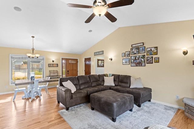 living room featuring lofted ceiling, ceiling fan with notable chandelier, and light wood-type flooring