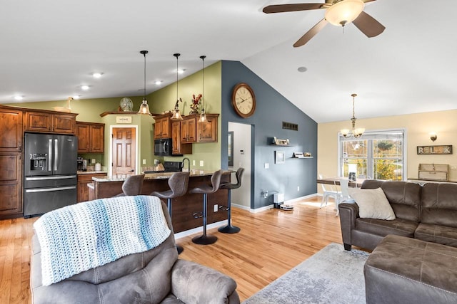 living room with lofted ceiling, sink, ceiling fan with notable chandelier, and light hardwood / wood-style floors