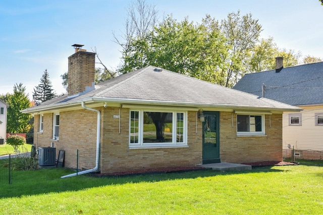 rear view of property featuring a yard and central air condition unit