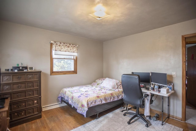 bedroom with baseboard heating and hardwood / wood-style flooring