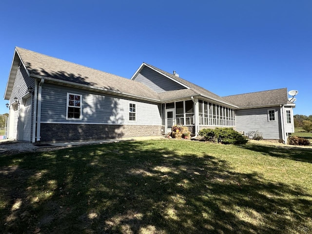 back of house with a sunroom, a lawn, and a garage