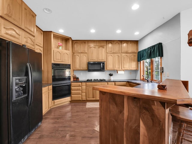 kitchen with kitchen peninsula, dark hardwood / wood-style flooring, black appliances, and sink