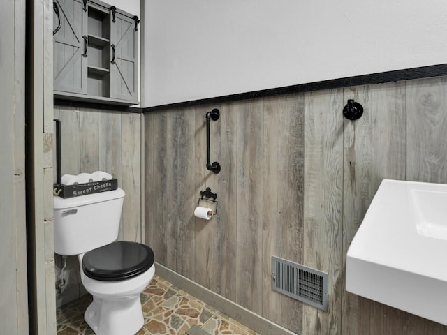 bathroom with wood walls and toilet