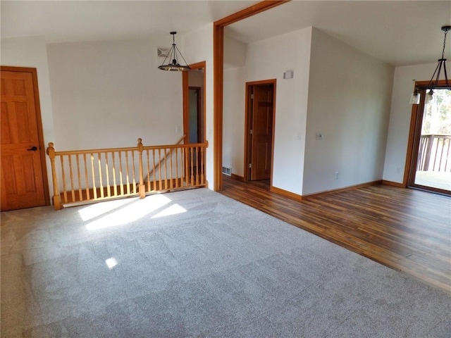 unfurnished room featuring vaulted ceiling, dark hardwood / wood-style floors, and an inviting chandelier