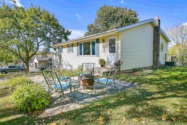 back of house with an outdoor fire pit, a patio, and a lawn