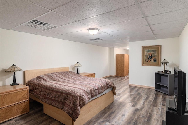 bedroom with dark hardwood / wood-style floors and a paneled ceiling