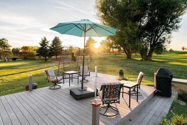 deck at dusk featuring a lawn and a grill