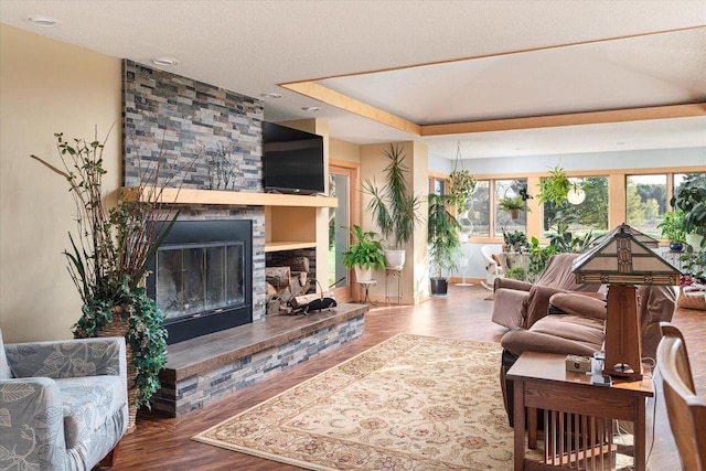 living room with a stone fireplace, a textured ceiling, and wood-type flooring