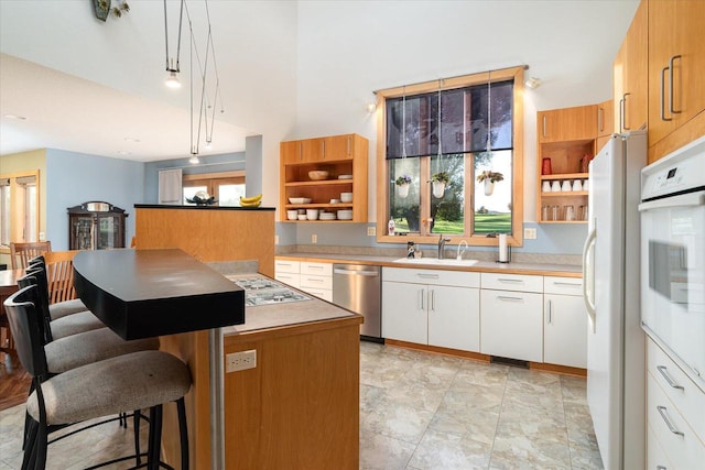 kitchen featuring white cabinetry, sink, a kitchen island, and white appliances