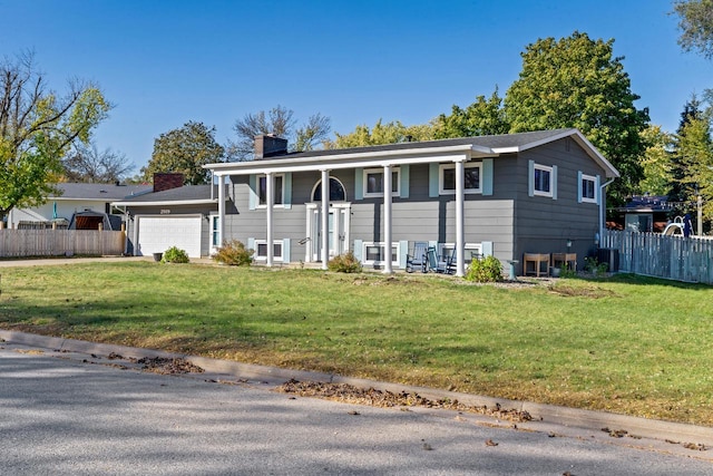 raised ranch with a front yard, a garage, and cooling unit