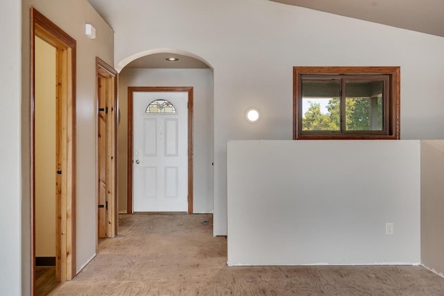 hallway with vaulted ceiling and light colored carpet