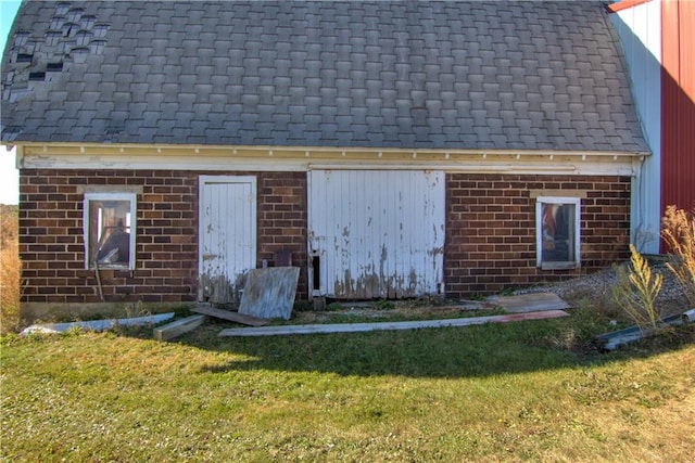 exterior space featuring a shingled roof, a lawn, and brick siding