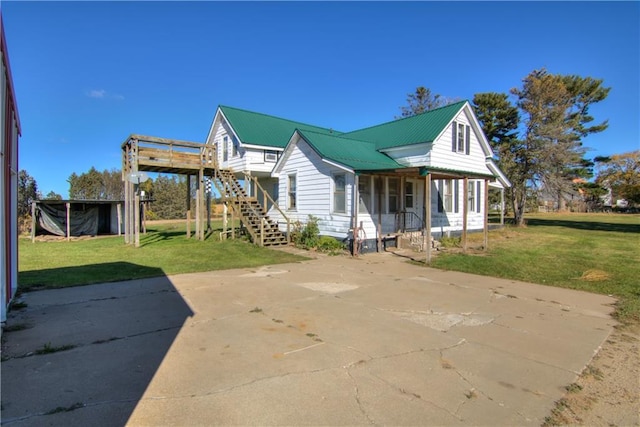 view of front facade featuring a porch, stairway, metal roof, and a front yard