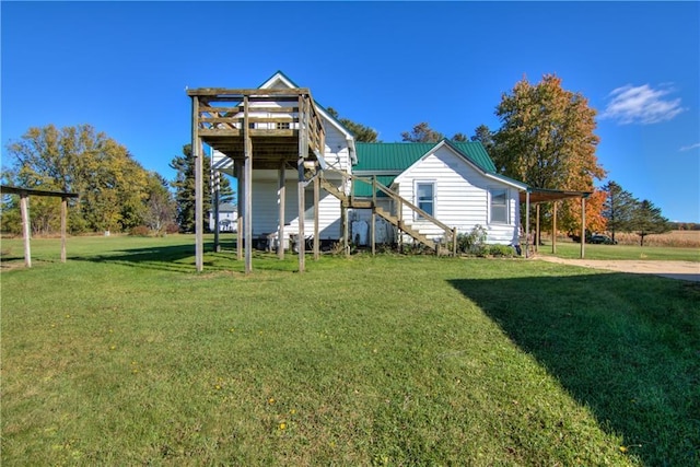 back of property with a wooden deck, stairs, metal roof, and a yard