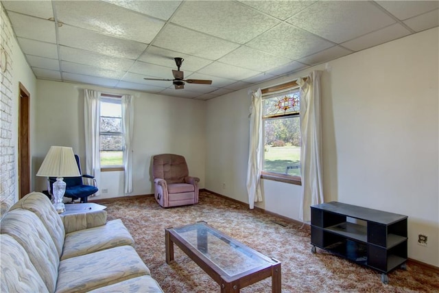 living room with baseboards, carpet flooring, ceiling fan, and a drop ceiling