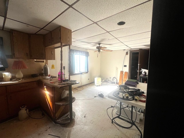 kitchen featuring ceiling fan and a drop ceiling