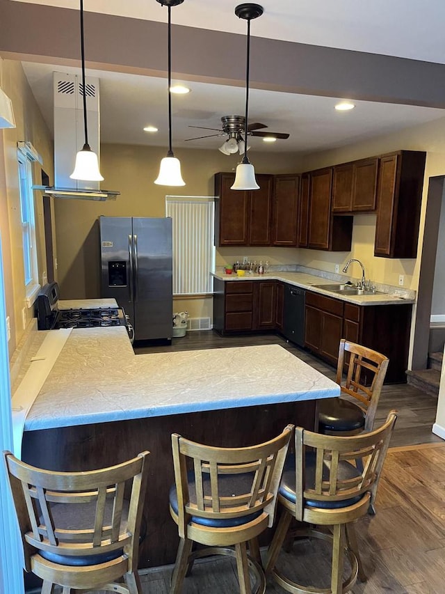 kitchen featuring hanging light fixtures, extractor fan, wood-type flooring, black appliances, and sink