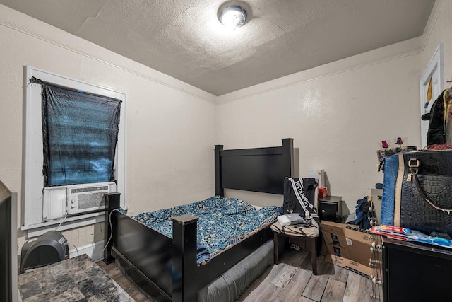 bedroom featuring crown molding, hardwood / wood-style flooring, cooling unit, and a textured ceiling