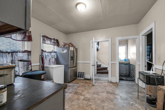 3221 N 38th St, Milwaukee, WI 53216 - kitchen featuring stainless steel refrigerator with ice dispenser, fridge, healthy amount of natural light, a textured ceiling, and stone finish floors