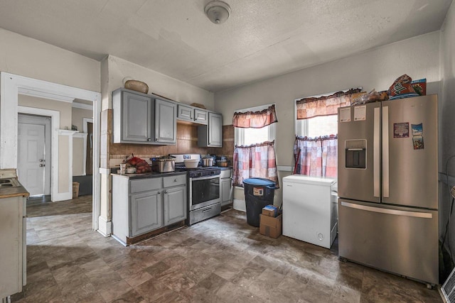 kitchen featuring gray cabinetry, tasteful backsplash, appliances with stainless steel finishes, and a textured ceiling