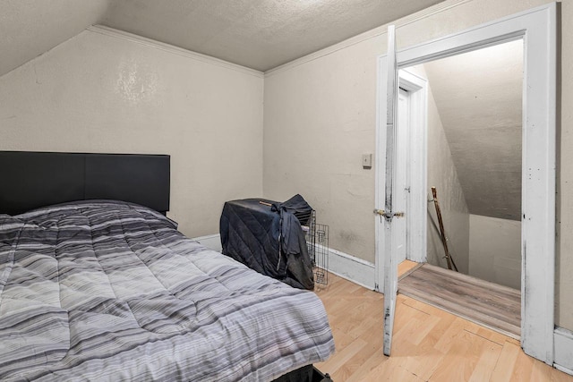 bedroom featuring crown molding, vaulted ceiling, wood-type flooring, and a textured ceiling