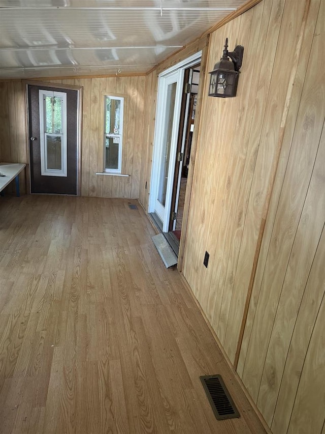 interior space with light hardwood / wood-style floors and wood walls