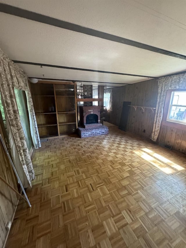 interior space featuring parquet flooring, wooden walls, a fireplace, and a textured ceiling