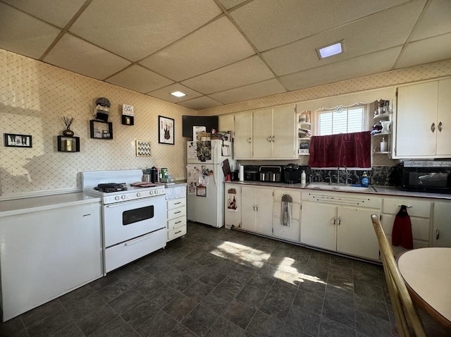 kitchen featuring sink, white cabinets, a paneled ceiling, and white appliances