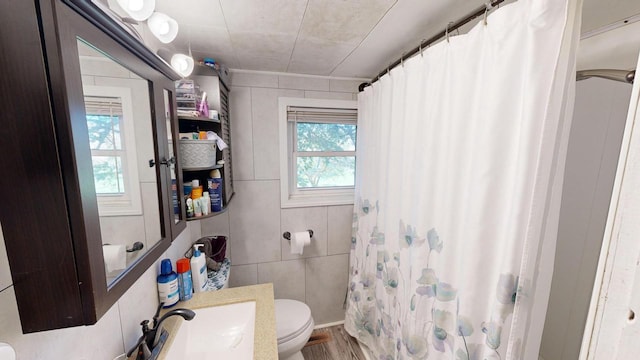 bathroom featuring a wealth of natural light, tile walls, a shower with curtain, and toilet