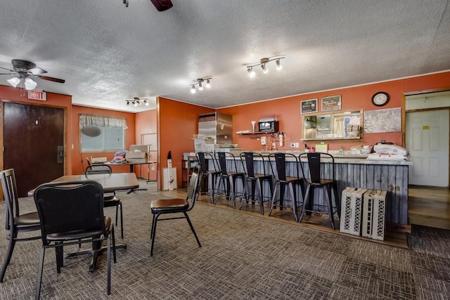 carpeted dining room featuring track lighting, a textured ceiling, and ceiling fan