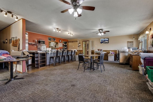 dining space with a textured ceiling, track lighting, dark carpet, and ceiling fan